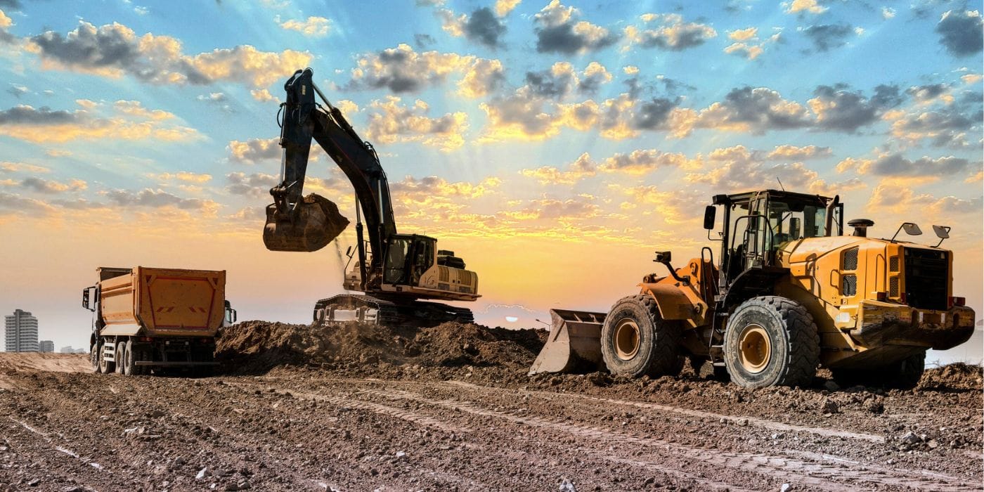 Excavator and wheel loader working a road corridor at sunset